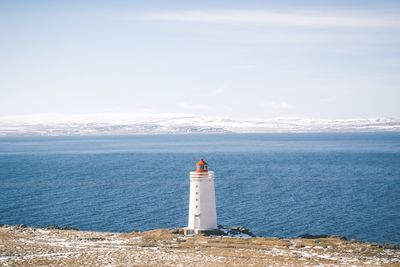 Lighthouse by sea against sky