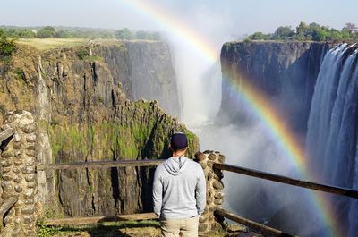 Rear view of man standing against waterfall