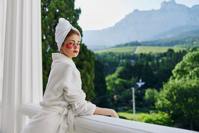 Portrait of young woman standing against trees