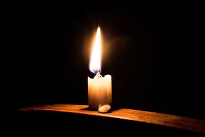 Close-up of illuminated candle in darkroom