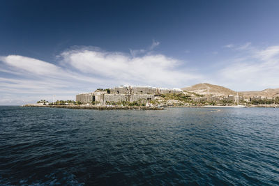 Scenic view of sea by buildings against sky