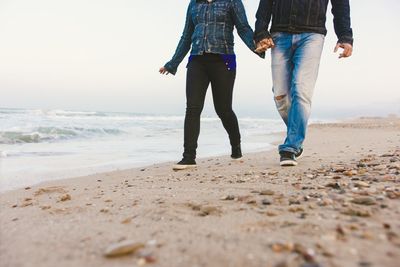 Low section of couple walking at beach