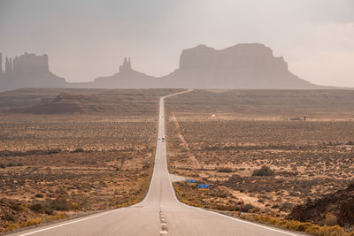 Road leading towards geological features in monument valley during summer