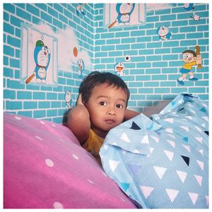 Portrait of cute baby girl on bed at home