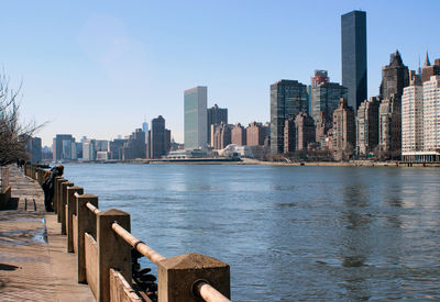 Buildings by river against sky in city