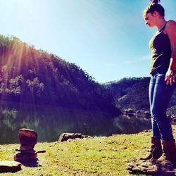 Side view of man standing by lake against sky