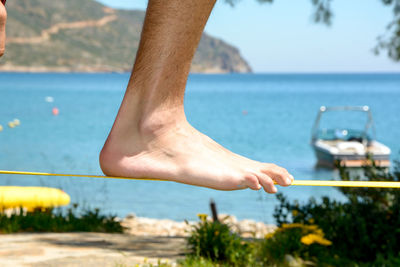 Low section of man slacklining at beach