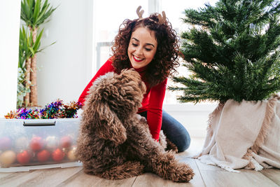 Portrait of smiling young woman sitting with her dog at christmas day