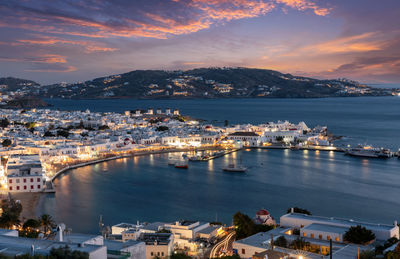 High angle view of illuminated city by sea against sky