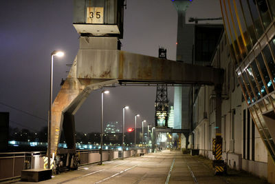 Illuminated road by bridge in city at night