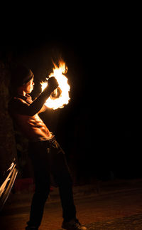 Midsection of man holding fire at night