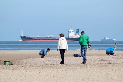 People at sandy beach against sky