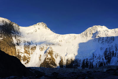 Low angle view of snowcapped mountain against clear blue sky