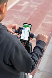 Young man on an electric skateboard using smartphone gps applications