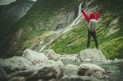 Rear view of man standing on rock against mountain