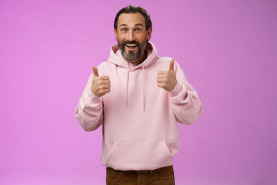 Portrait of smiling man standing against pink background