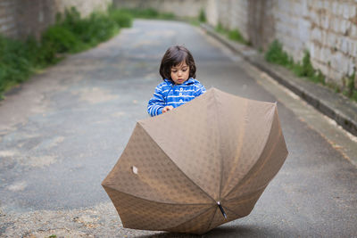 Little handsome baby boy playing with umbrella outdoor