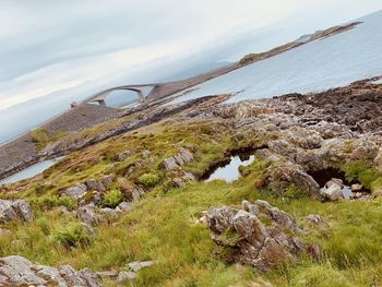 Scenic view of rocks by sea against sky