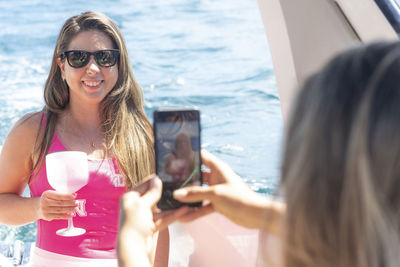 Female friends on top of a boat against the sea in the background.