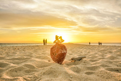 People at beach against sky during sunset