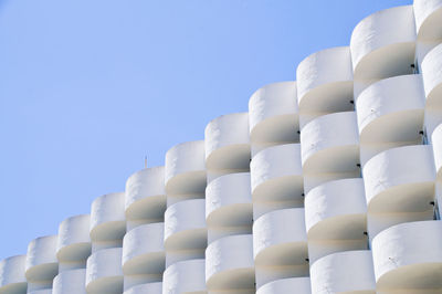 Low angle view of white hotel building with balkony against blue sky