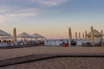 People on beach against sky during sunset