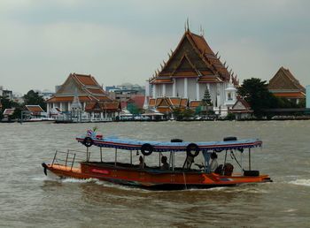 Boat in river by building against sky