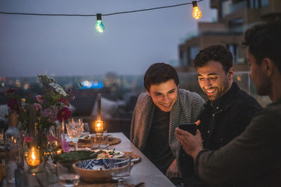 People on table in illuminated city