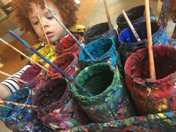 Close-up of boy with colorful messy paint containers at home