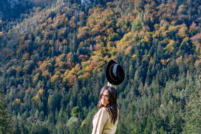 Portrait of woman standing by tree in forest