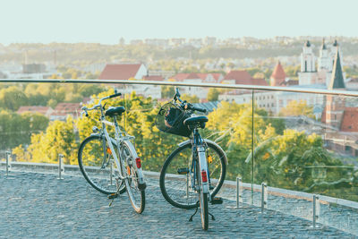 Bicycle by river in city against clear sky