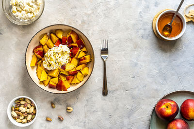 Healthy fruit salad with nectarine, ricotta cream with pistachios and honey, top view. copy space