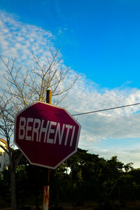 Low angle view of road sign against blue sky