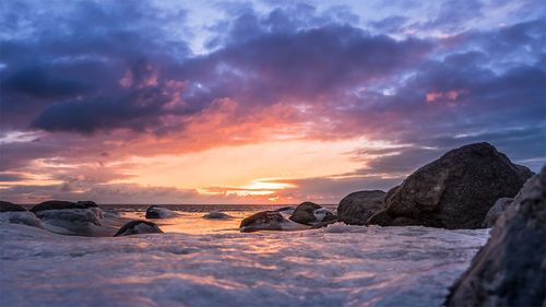 Rocks on shore against sky during sunset