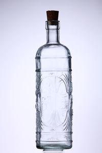 Close-up of corked glass bottle against white background