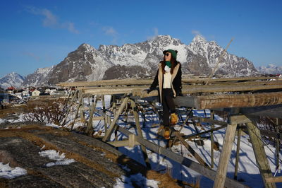 Woman standing on snow covered mountain against sky