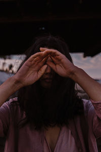 Close-up of woman covering face with hand