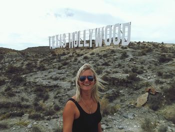 Portrait of young woman standing against hollywood sign