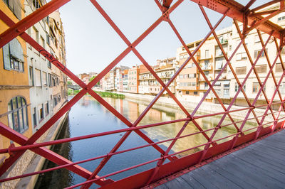 Bridge over river by buildings against sky