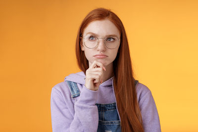 Portrait of beautiful young woman against orange background