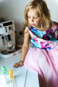 Little girl in elegant dress sitting on a table in the kitchen