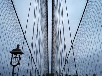 Low angle view of suspension bridge against cloudy sky