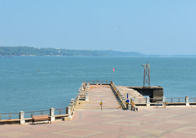 Pier on sea against clear blue sky