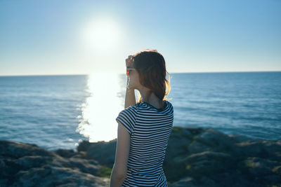 Woman standing by sea against sky