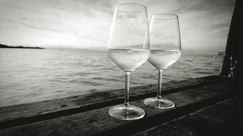 Close-up of wineglasses against lake