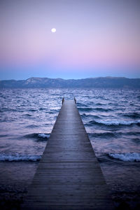 Pier over sea against sky at sunset