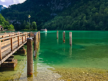 Wooden posts and ship in lake against trees