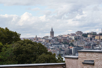 View of buildings in city against cloudy sky