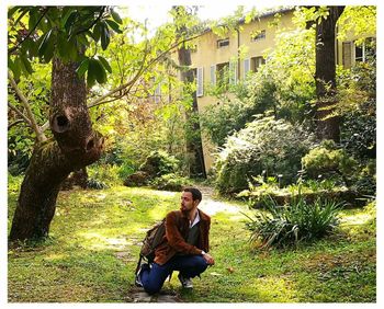 Woman sitting on grass against trees