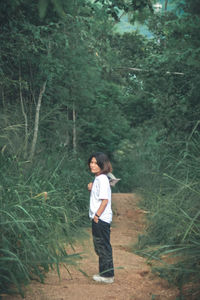 Full length of teenage girl standing in forest